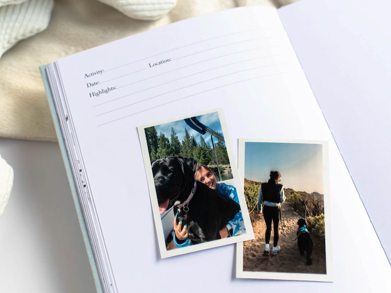 May include: Open journal with lined pages and prompts for Activity, Date, and Highlights. Two photos are attached: one of a person with a black dog, and another of a person hiking with a black dog. The journal is open on a white surface.