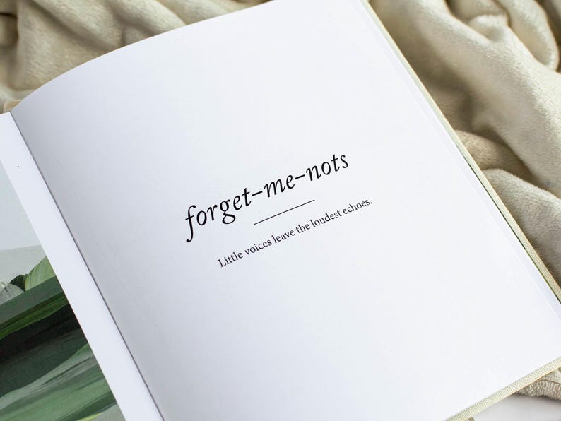 May include: Open book with the words "forget-me-nots" in a delicate serif font, underlined. Below, the text reads "Little voices leave the loudest echoes." The pages are white, and the book is open on a soft, neutral-toned surface.