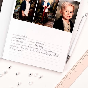 K&ouml;nnte beinhalten: Eine wei&szlig;e Seite mit handschriftlichen Notizen &uuml;ber den ersten Schultag eines Kindes. Die Notizen beinhalten den Namen des Kindes, Titus, das Datum, Oktober 2015, die Klasse, Vorschule, die Schule, Wee Cove, die Lehrerin, Frau Amy, und das Lieblingsfach oder die Lieblingsaktivit&auml;t des Kindes, Malen und Bauen mit Spielzeug. Die Seite enth&auml;lt auch einen H&ouml;hepunkt: "Mit 3 1/2 Jahren ist dies dein erstes Mal in der Schule und du liebst es!"