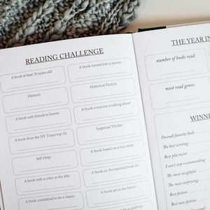 K&ouml;nnte beinhalten: Eine Lesechallenge-Checkliste mit Aufforderungen wie "Ein Buch, das mindestens 20 Jahre alt ist" und "Ein Buch, das verfilmt wurde". Die Checkliste befindet sich auf einer wei&szlig;en Seite mit schwarzem Text. Die Seite ist auf einen Abschnitt mit dem Titel "Das Jahr im R&uuml;ckblick" ge&ouml;ffnet, mit Aufforderungen f&uuml;r "Anzahl der gelesenen B&uuml;cher", "meistgelesenes Genre" und "Anzahl der Sterne".