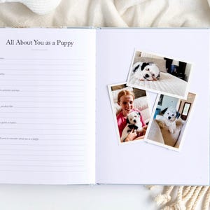 May include: Open notebook with the text "All About You as a Puppy" and lined pages. Three photos of a puppy are on the right page. The puppy is black and white. The notebook is on a white surface.
