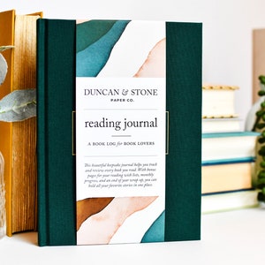 K&ouml;nnte beinhalten: Ein gr&uuml;nes Lesetagebuch mit dem Titel "reading journal" und dem Text "A BOOK LOG for BOOK LOVERS" auf dem Cover. Das Cover zeigt au&szlig;erdem ein Aquarelldesign mit abstrakten Formen in Blaut&ouml;nen, Gr&uuml;n- und Oranget&ouml;nen.