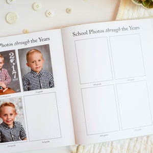 May include: A school photo album with blank spaces for photos from kindergarten through 8th grade. The album has a white background and black text. The album is open to a page with photos of a young boy in kindergarten, 1st, and 2nd grade.