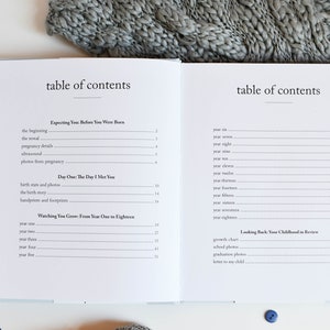 May include: A white book with a blue cover and the title "table of contents" printed on the front. The book is open to a page with a table of contents for a baby memory book. The table of contents includes sections for "Expecting You Before You Were Born", "Day One: The Day I Met You", "Watching You Grow: From Year One to Eighteen", and "Looking Back: Your Childhood in Review".