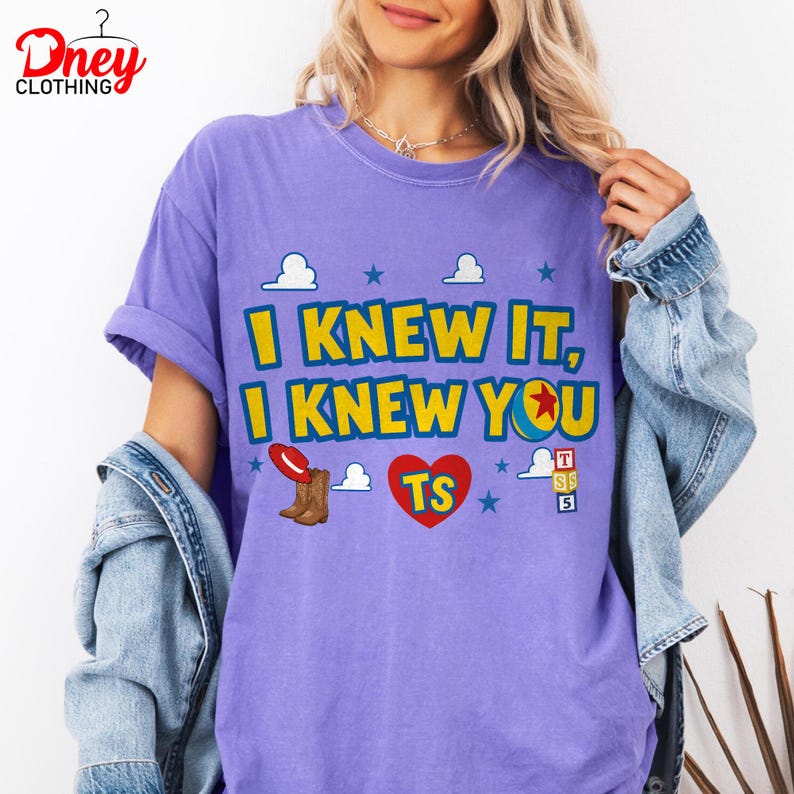 Puede incluir: Una camiseta morada con el texto amarillo I KNEW IT, I KNEW YOU, un sombrero de vaquero rojo, botas marrones, un coraz&oacute;n rojo con las letras TS, una pelota colorida con una estrella roja y tres bloques apilados con T, S y 5, con estrellas y nubes azules.