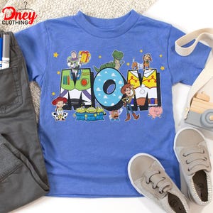 May include: A light blue t-shirt with the word "MOM" and Toy Story characters. The "M" is designed as Buzz Lightyear's suit, the "O" has a blue cloud pattern, and the "M" is designed as Woody's vest. Other characters include Rex, Slinky Dog, and the Little Green Men.