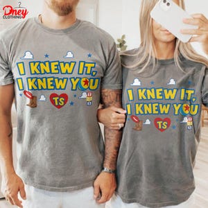 Puede incluir: Una camiseta gris con el texto amarillo I KNEW IT, I KNEW YOU, un coraz&oacute;n rojo con las letras TS, una bota de vaquero marr&oacute;n, peque&ntilde;as estrellas azules, nubes blancas y una peque&ntilde;a pila de bloques de colores con las letras T, S y el n&uacute;mero 5.