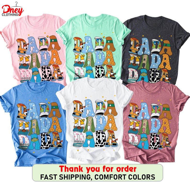 May include: A collection of six t-shirts in various colors, including pink, mint green, charcoal, blue, white, and mauve. Each shirt features the word "DADA" in a playful, colorful font with decorative patterns. The shirts are casual wear.