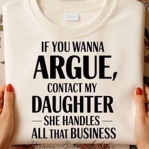 May include: Cream-colored sweatshirt with the text "IF YOU WANNA ARGUE, CONTACT MY DAUGHTER - SHE HANDLES ALL THAT BUSINESS" in bold black letters. The sweatshirt is held by hands with red nail polish.