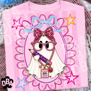 Puede incluir: Una camiseta rosa claro con el gr&aacute;fico de un fantasma blanco que lleva gafas de estampado de leopardo rosa y un lazo a juego. El fantasma sostiene un l&aacute;piz morado y rosa y lleva un collar con un dije que dice TEACHER BOO CREW.