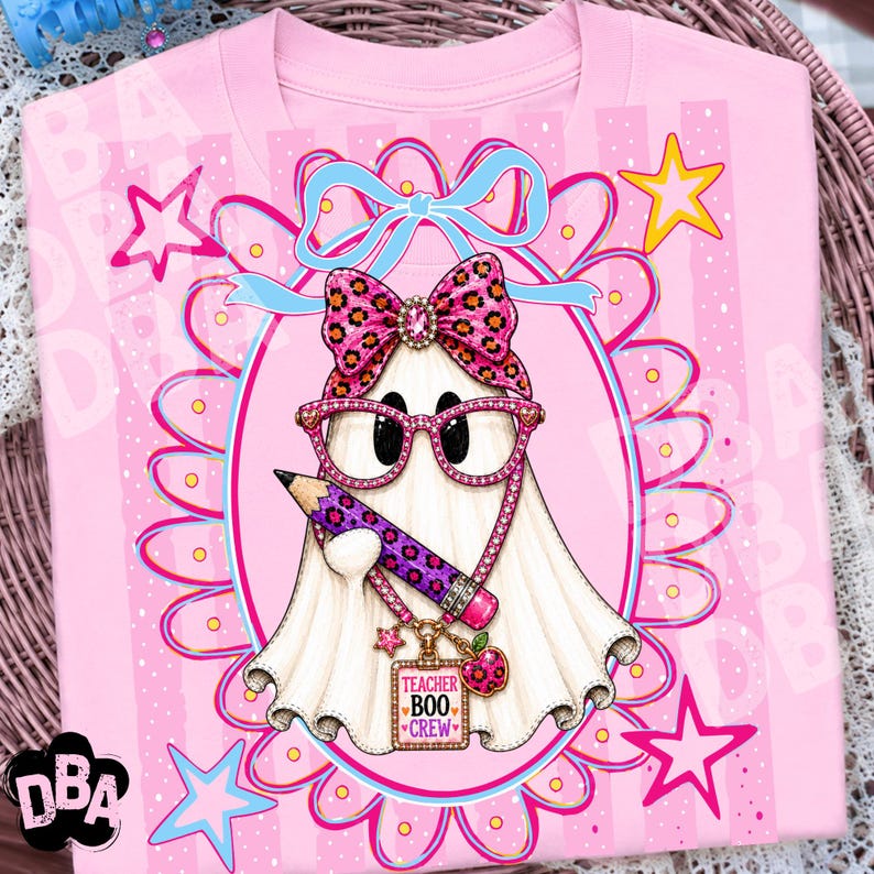 Puede incluir: Una camiseta rosa claro con el gr&aacute;fico de un fantasma blanco que lleva gafas de estampado de leopardo rosa y un lazo a juego. El fantasma sostiene un l&aacute;piz morado y rosa y lleva un collar con un dije que dice TEACHER BOO CREW.