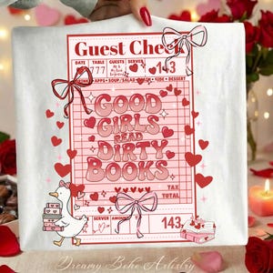 May include: White t-shirt with a pink graphic of a restaurant guest check that reads "Good Girls Read Dirty Books." The design includes hearts, bows, and a cartoon goose carrying books. The text "Dreamy Boho Artistry" is at the bottom.