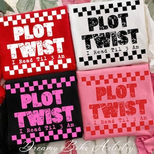 以下が含まれることがあります： 赤、白、黒、ピンクの4色のTシャツ。各Tシャツには「PLOT TWIST」と「I Read Til 3 Am」の文字がプリントされています。文字は対照的な色で、チェック柄のパターンで縁取られています。