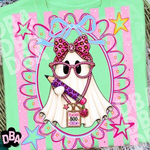Puede incluir: Una camiseta verde claro con un gr&aacute;fico central de un fantasma blanco con gafas de estampado de leopardo rosa y un lazo a juego. El fantasma sostiene un l&aacute;piz morado y lleva un collar con una etiqueta que dice TEACHER BOO CREW.