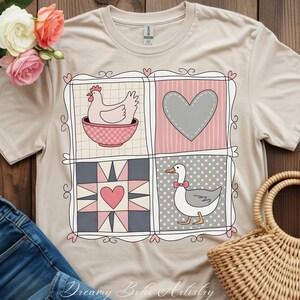 May include: Beige t-shirt featuring a patchwork design with a chicken in a bowl, a gray heart, a pink heart in a starburst, and a goose with a bow tie. The shirt has the text "Dreamy Boho Artistry" at the bottom.