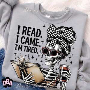 May include: A light gray sweatshirt with a graphic of a skeleton wearing sunglasses and a checkered bow, reading a book and holding a coffee cup. Text reads: "I READ. I CAME. I'M TIRED."