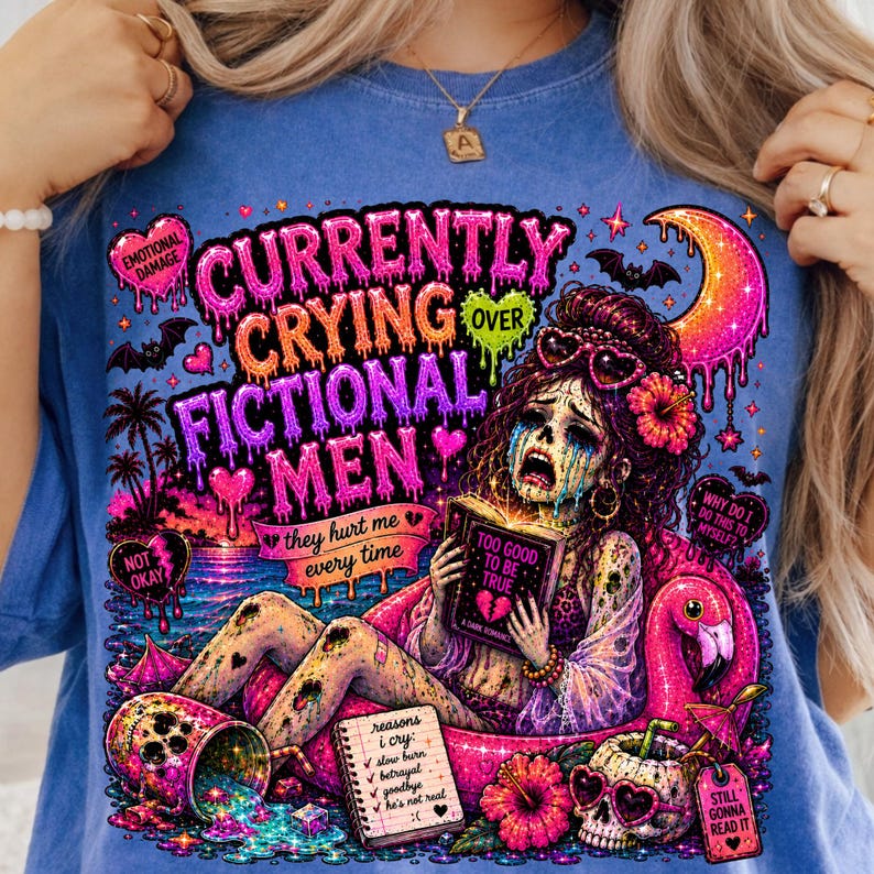 Puede incluir: Camiseta azul con un gr&aacute;fico colorido. El gr&aacute;fico muestra a una mujer llorando leyendo un libro titulado "Too Good To Be True". El texto incluye "Currently Crying Over Fictional Men" y "They Hurt Me Every Time."