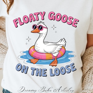 May include: White t-shirt with a cartoon illustration of a goose wearing sunglasses and a pink and orange inflatable ring. The text "Floaty Goose on the Loose" is printed on the shirt.