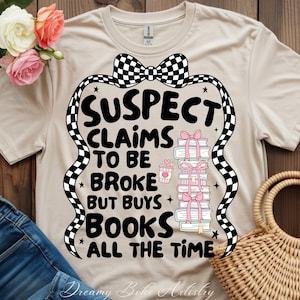 Puede incluir: Camiseta beige con el texto negro "SUSPECT CLAIMS TO BE BROKE BUT BUYS BOOKS ALL THE TIME". El diseño incluye una pila de libros atados con lazos rosas, una taza de café y un lazo a cuadros.