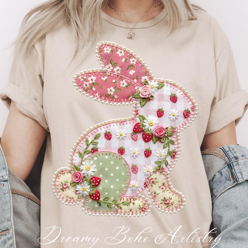 May include: Beige t-shirt featuring a decorative bunny design. The bunny is crafted with pink floral fabric, white gingham, and green polka dots, adorned with strawberries, daisies, and roses. The text "Dreamy Boho Artistry" is at the bottom.