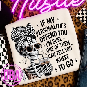 Puede incluir: Sudadera crema con un esqueleto con gafas de sol y un lazo a cuadros, sosteniendo una bebida. El texto dice: "Si mis personalidades te ofenden, estoy seguro de que una de ellas puede decirte a dónde ir."
