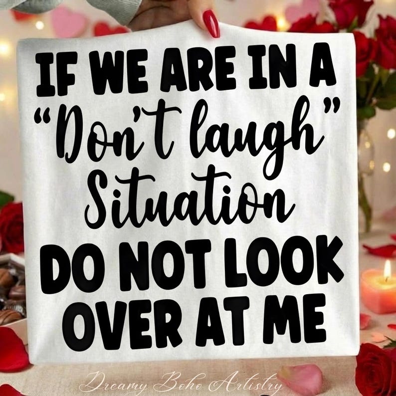 May include: White t-shirt with the text "IF WE ARE IN A "Don't laugh" Situation DO NOT LOOK OVER AT ME" in black. The shirt has the Dreamy Boho Artistry logo at the bottom.