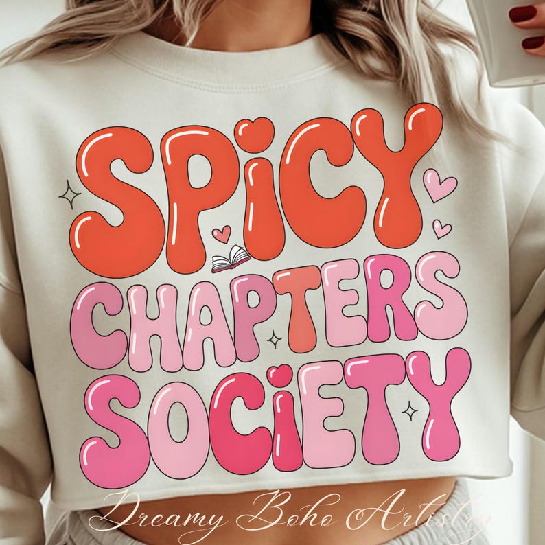 May include: Cream-coloured cropped sweatshirt featuring the text "SPICY CHAPTERS SOCIETY" in a retro font. The text is in shades of red and pink, with heart and star accents. The words "Dreamy Boho Art" are at the bottom.