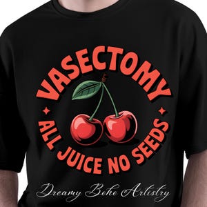 May include: Black t-shirt with a circular design featuring two red cherries and the text "VASECTOMY ALL JUICE NO SEEDS" in orange. The shirt also includes the text "Dreamy Boho Artistry" in a cursive font.