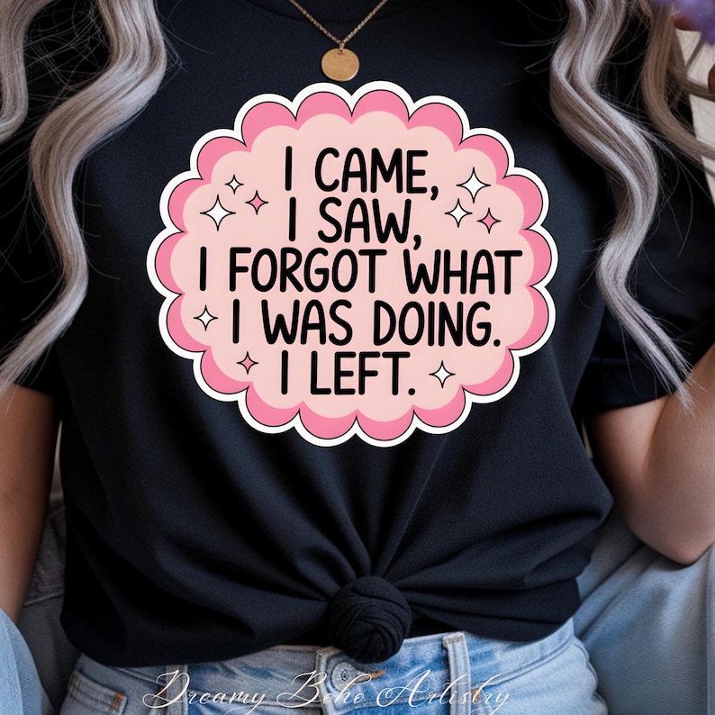 May include: Black t-shirt with a pink and white graphic. The graphic reads "I CAME, I SAW, I FORGOT WHAT I WAS DOING. I LEFT." The design is in a cloud shape with star accents. The shirt is knotted at the waist.