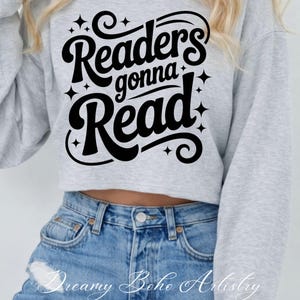 K&ouml;nnte beinhalten: Ein hellgraues, gecropptes Sweatshirt mit dem schwarzen Text "Readers gonna Read". Das Sweatshirt hat einen Rundhalsausschnitt und lange &Auml;rmel. Der untere Teil des Bildes zeigt blaue Jeans.