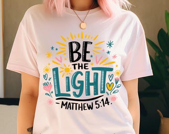 May include: White t-shirt with a colorful graphic design that says "Be the Light - Matthew 5:14".