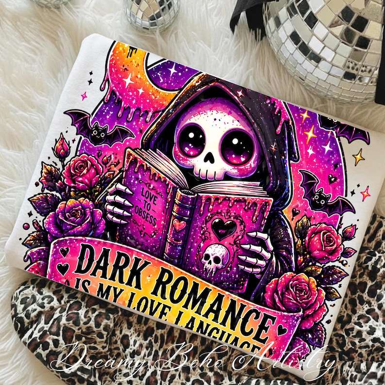 May include: White sweatshirt with a colorful graphic of a cartoon Grim Reaper reading a book. The design includes bats, roses, and the text "DARK ROMANCE IS MY LOVE LANGUAGE".