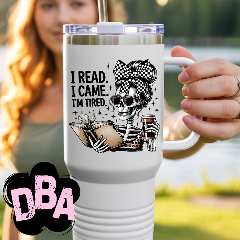 May include: White travel mug with a black and white skeleton graphic wearing sunglasses and a checkered bow. The skeleton is holding a book and a coffee cup. Text on the mug reads: "I READ. I CAME. I'M TIRED."