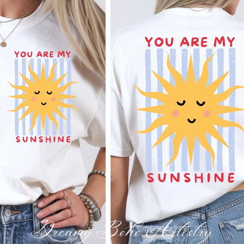 May include: White t-shirt with a yellow sun graphic and the text "YOU ARE MY SUNSHINE" in red. The sun has a smiling face and is set against blue vertical stripes. The design is on the front and back of the shirt.