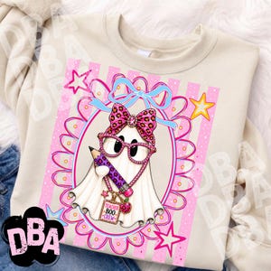 Puede incluir: Una sudadera beige con el gr&aacute;fico de un fantasma blanco con gafas y lazo de estampado de leopardo rosa. El fantasma sostiene un l&aacute;piz morado y lleva una etiqueta que dice Teacher BOO CREW. El dise&ntilde;o est&aacute; enmarcado por un &oacute;valo festoneado rosa.