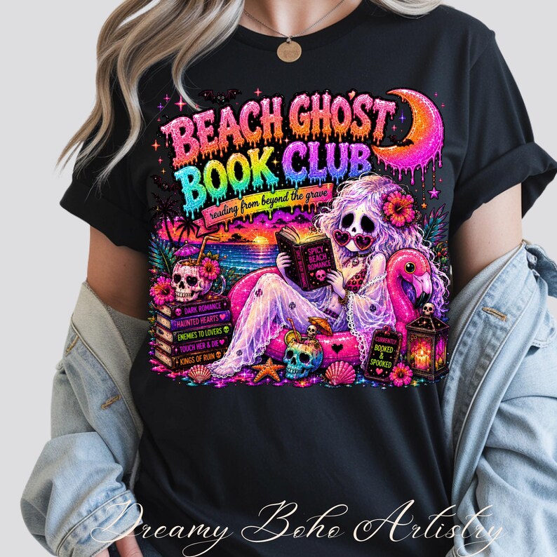 Puede incluir: Camiseta negra con un gr&aacute;fico colorido. Presenta el texto "BEACH GHOST BOOK CLUB" y una sirena leyendo un libro. El dise&ntilde;o incluye calaveras, un flamenco y una escena de puesta de sol. Tambi&eacute;n incluye el texto "reading from beyond the grave".