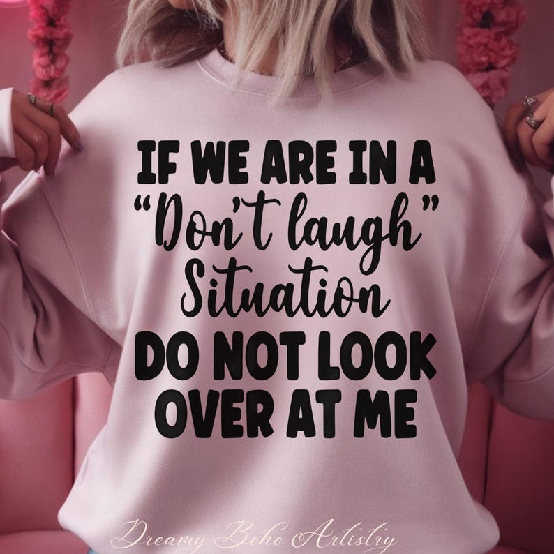 May include: A light pink sweatshirt with the text "IF WE ARE IN A 'Don't laugh' Situation DO NOT LOOK OVER AT ME" in black. The words "Dreamy Boho Artistry" are at the bottom.