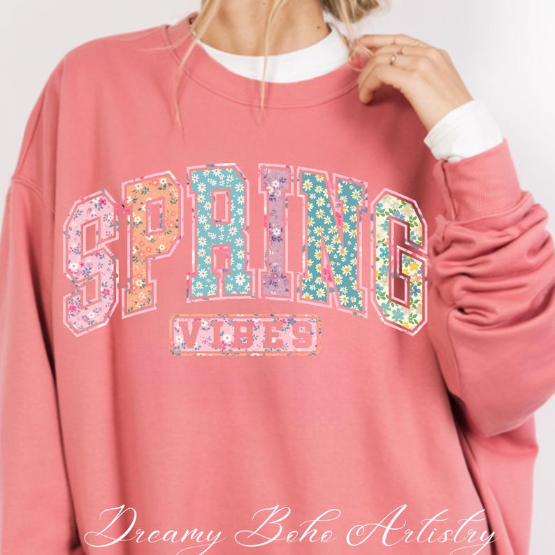 May include: A coral-colored sweatshirt with the word "SPRING" in a floral design across the chest, and the word "VIBES" below it. The sweatshirt has long sleeves and a crew neck. The text "Dreamy Boho Artistry" is at the bottom.