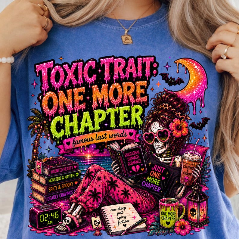 Puede incluir: Camiseta azul con un gr&aacute;fico colorido que presenta un esqueleto leyendo un libro con el texto "TOXIC TRAIT: ONE MORE CHAPTER". El dise&ntilde;o incluye libros, una taza de caf&eacute; y una luna creciente. El reloj muestra las 02:46 AM.