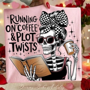 Può includere: T-shirt rosa con uno scheletro con occhiali da sole, un fiocco a scacchi e una tazza di caffè, che legge un libro. Il testo recita "RUNNING ON COFFEE & PLOT TWISTS".