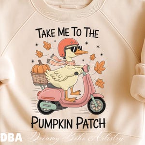 May include: Cream-colored sweatshirt with a graphic of a duck riding a pink scooter, wearing sunglasses, a helmet, and a scarf. The text "TAKE ME TO THE PUMPKIN PATCH" is above and below the duck. A pumpkin is in a basket.