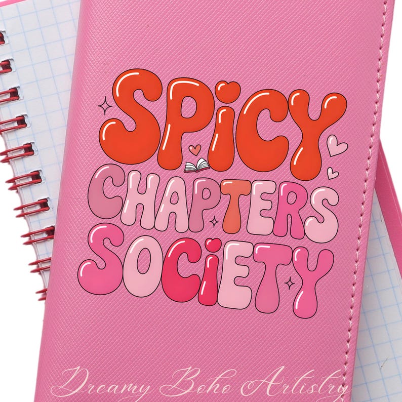 May include: A pink notebook cover with the text "SPICY CHAPTERS SOCIETY" in orange and pink bubble letters. The cover also features small heart and star graphics. The words "Dreamy Boho Artistry" are written in cursive at the bottom.