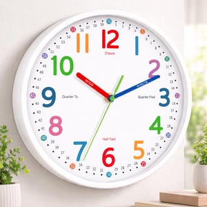 Peut inclure: Horloge murale ronde blanche avec des chiffres et des aiguilles colorés. Le cadran affiche les chiffres de 1 à 12 dans différentes couleurs, avec les mots "Heure" et "Minute" sur les aiguilles. Conçue pour l'apprentissage.