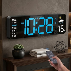 May include: Black rectangular digital clock displaying the time 10:28 PM in blue numerals, with the day of the week on the left and weather information on the right. The temperature is 76°F. Includes a remote control.