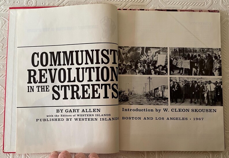 Puede incluir: Libro abierto con el t&iacute;tulo "COMMUNIST REVOLUTION IN THE STREETS" de Gary Allen. La portada presenta texto negro sobre fondo blanco, con fotos hist&oacute;ricas en blanco y negro. Publicado por Western Islands en 1967.