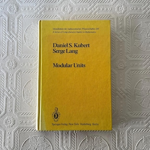 以下が含まれることがあります： ダニエル・S・クベルトとセルジュ・ラングによる「Modular Units」というタイトルの黄色のハードカバー本。本には黒い文字とSpringer-Verlagのロゴがあります。「Grundlehren der mathematischen Wissenschaften」シリーズの一部です。