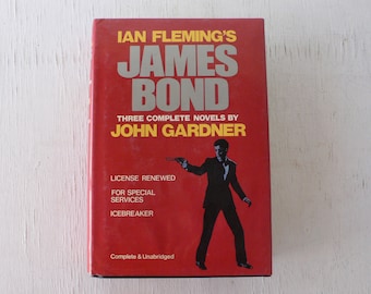 Könnte beinhalten: Ein rotes Taschenbuch mit dem Titel "IAN FLEMING'S JAMES BOND" und dem Untertitel "THREE COMPLETE NOVELS BY JOHN GARDNER". Das Cover zeigt eine Schwarzweißillustration eines Mannes im Anzug, der eine Waffe hält.