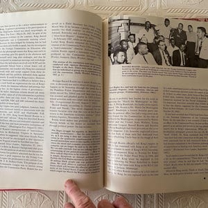 Puede incluir: Un libro abierto con texto y una fotograf&iacute;a en blanco y negro de un grupo de hombres. Las p&aacute;ginas son blancas con texto negro. El libro est&aacute; abierto en las p&aacute;ginas 60 y 61. El libro tiene un lomo rojo.