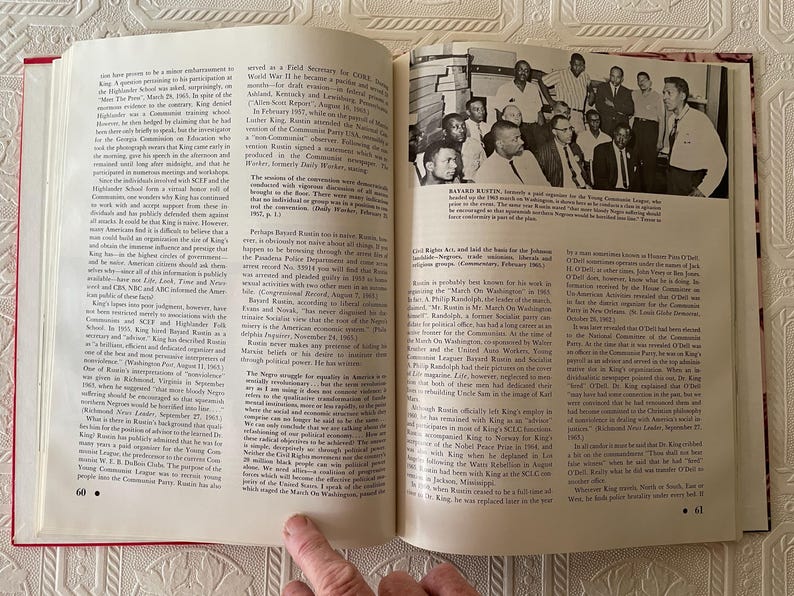 Puede incluir: Un libro abierto con texto y una fotograf&iacute;a en blanco y negro de un grupo de hombres. Las p&aacute;ginas son blancas con texto negro. El libro est&aacute; abierto en las p&aacute;ginas 60 y 61. El libro tiene un lomo rojo.