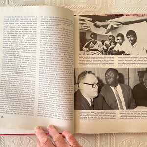 Puede incluir: Libro abierto con fotograf&iacute;as y texto en blanco y negro. Las im&aacute;genes muestran a un grupo de personas en una mesa y a tres hombres con trajes. El texto est&aacute; en negro.